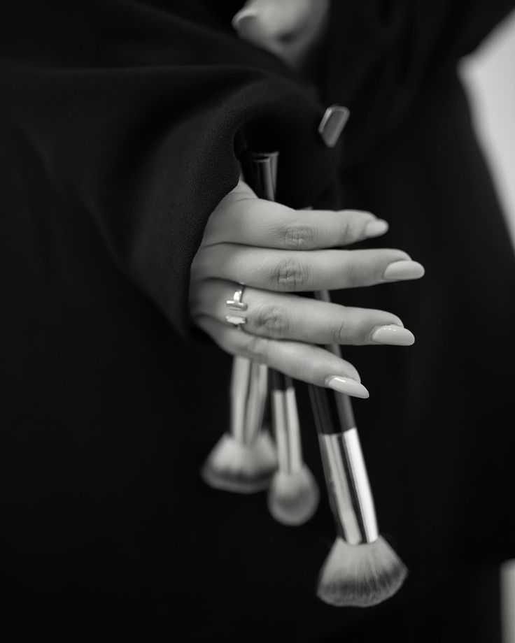 Hand holding a set of makeup brushes, black and white